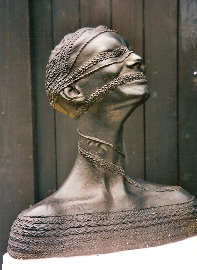Bronze sculpture of a woman's head and shoulders wrapped in chains