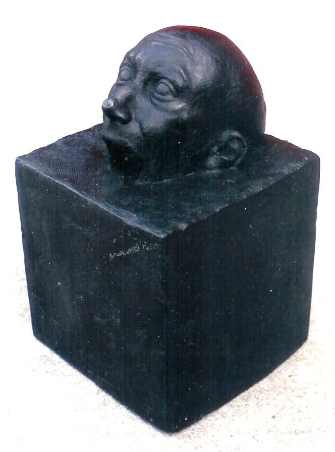 A bronze sculpture of head on a square block
